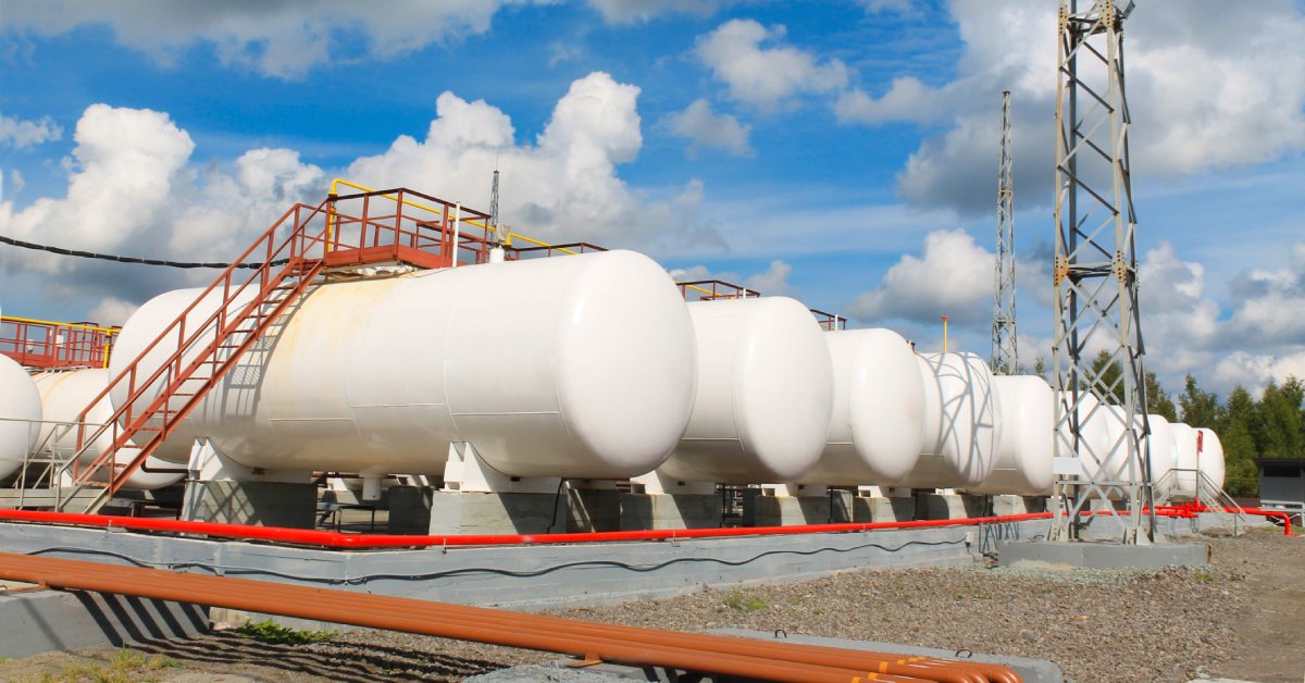 Numerous horizontal storage tanks all sitting next to each other on a large concrete slab.