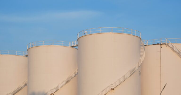 Some large white storage tanks sitting in the distance. Each tank has a large staircase running around it.