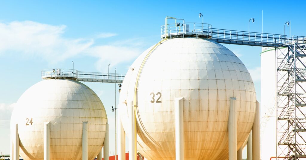 Some large spherical tanks standing next to each other. Each one has scaffolding going to the top of the tanks.