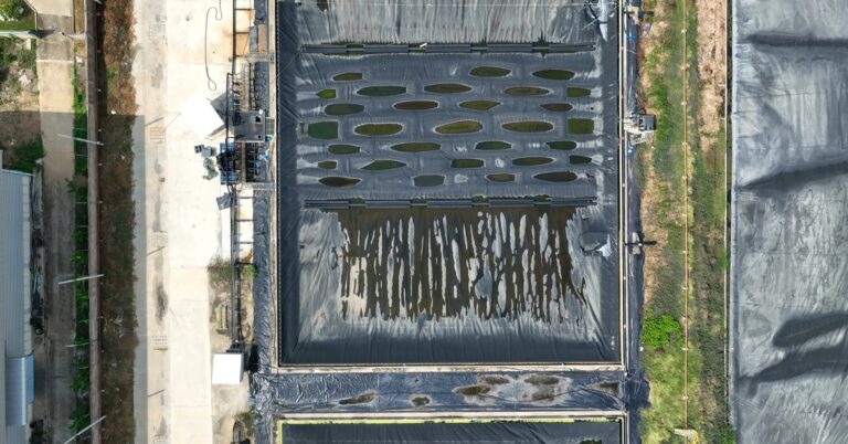 An aerial view of a field with spill containment liners. There are pools of liquid spread out over the liners.