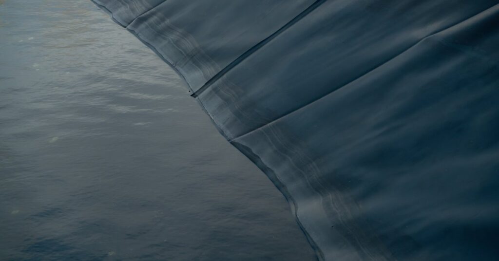 A close-up of a black liner with several wrinkles filled with water that takes up about half the picture.