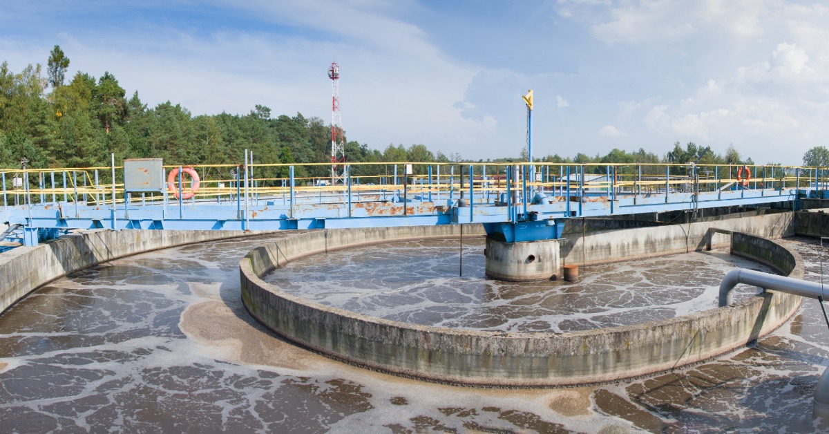 A large water treatment plant with various containment tanks holding water and pipes running between them.